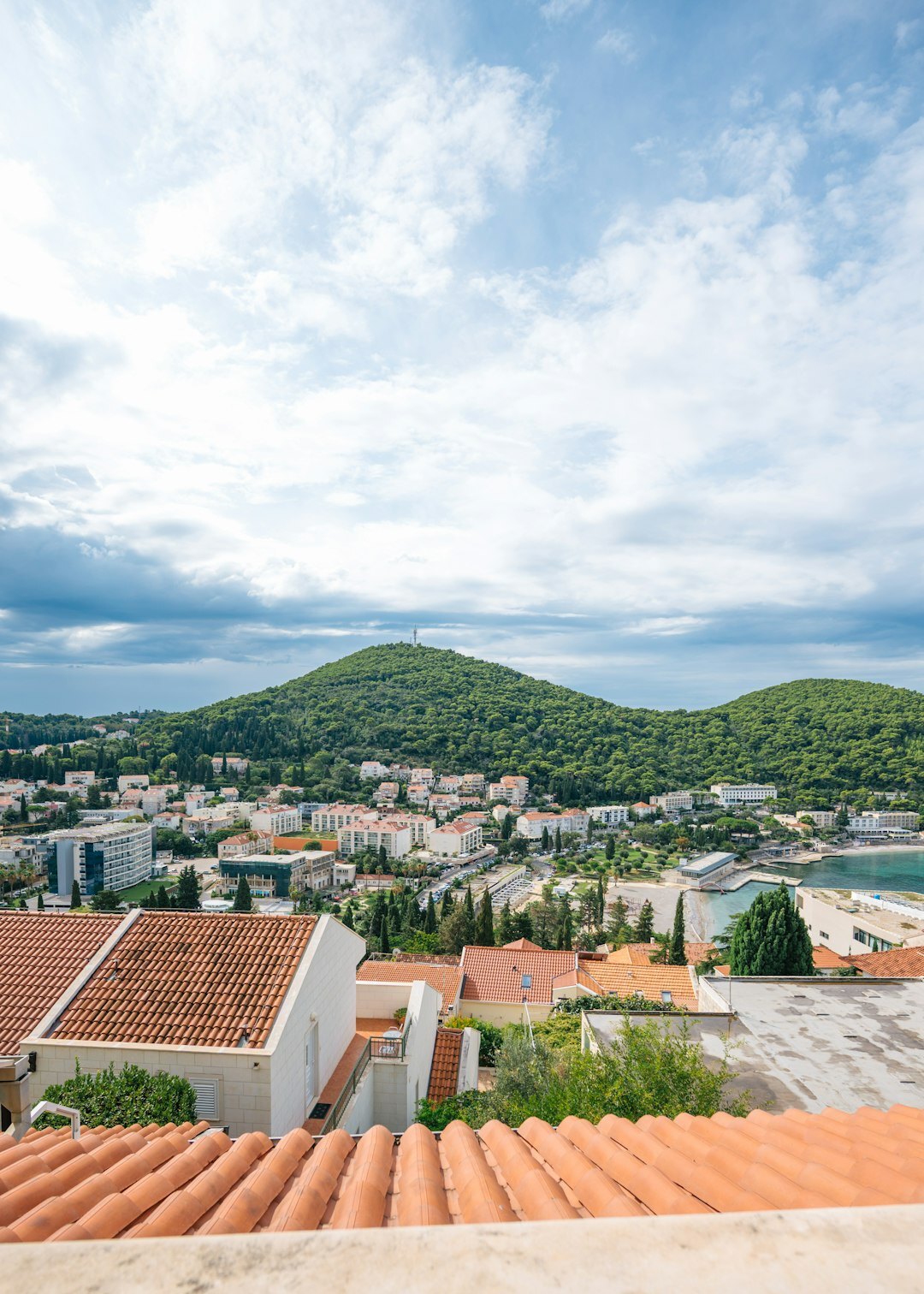 Photographer setting up a tripod and camera on a hillside overlooking a Croatian town